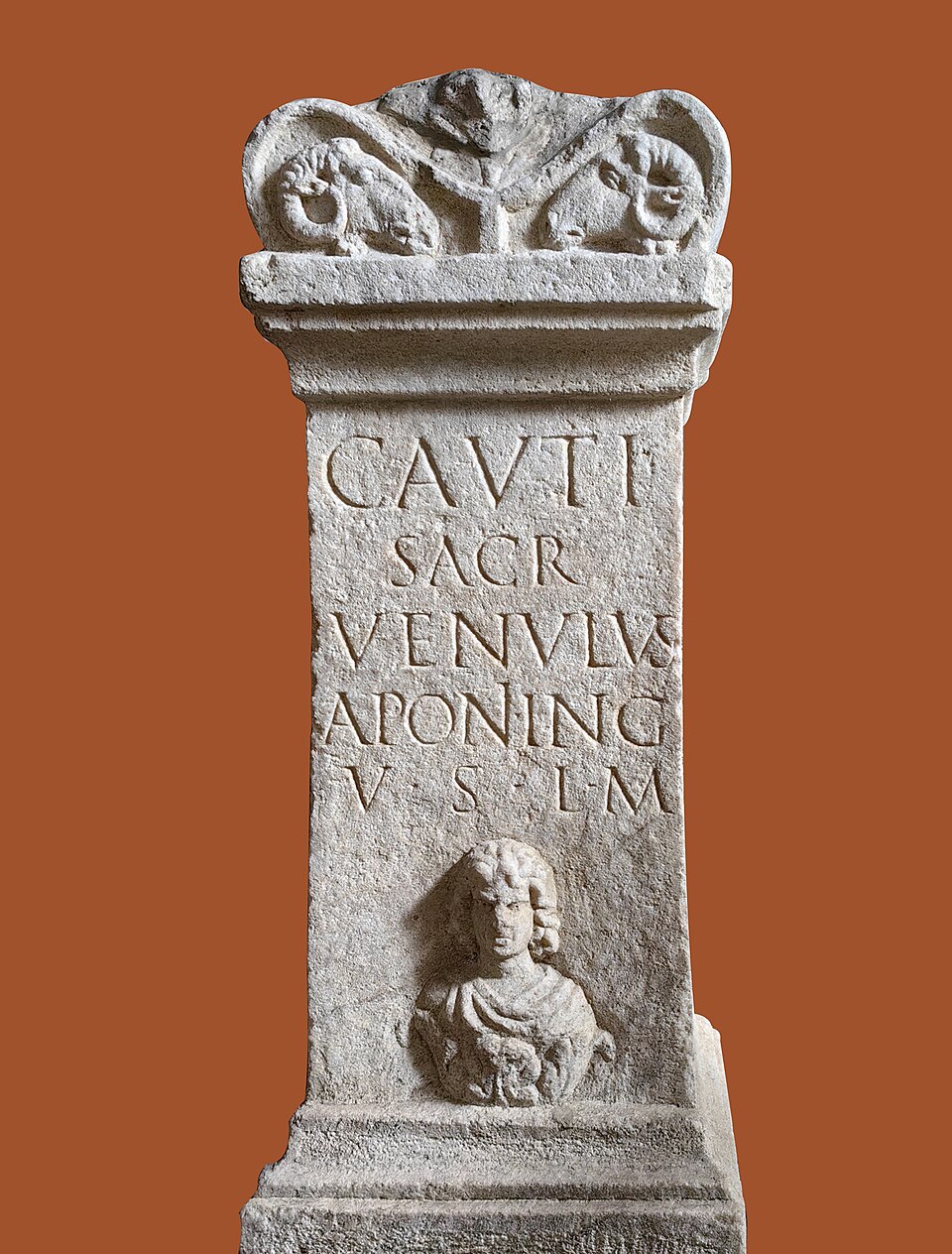 White marble altar from Mithraeum I at Ptuj, dedicated to Cautes by Venulus and decorated with a bust of the god emerging from foliage.