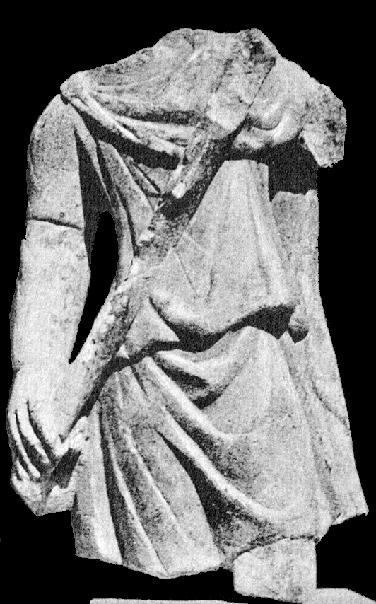 Marble statue of Cautes, found at Ostia. The head, one arm and the legs are missing. The figure wears a short tunic and raises the torch in the canonical upward gesture.